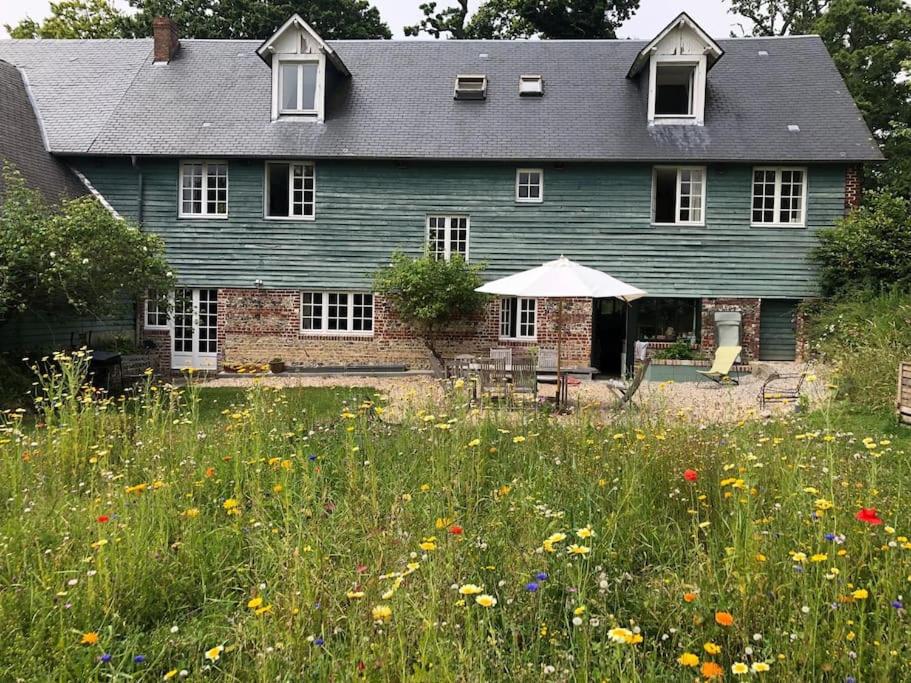 une maison bleue avec un champ de fleurs devant elle dans l'établissement Nouveau - Le Bois d'Hautôt, à Hautot-sur-Mer