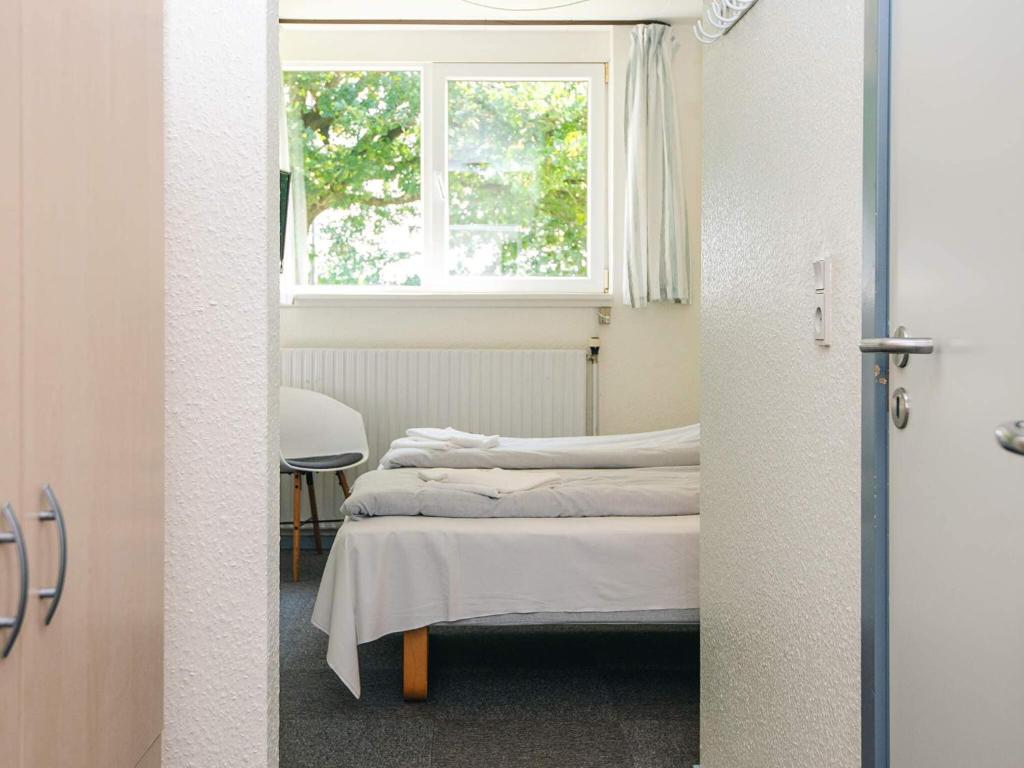 two beds in a room with a window at Splendid cabin in camping resort in Aabenraa