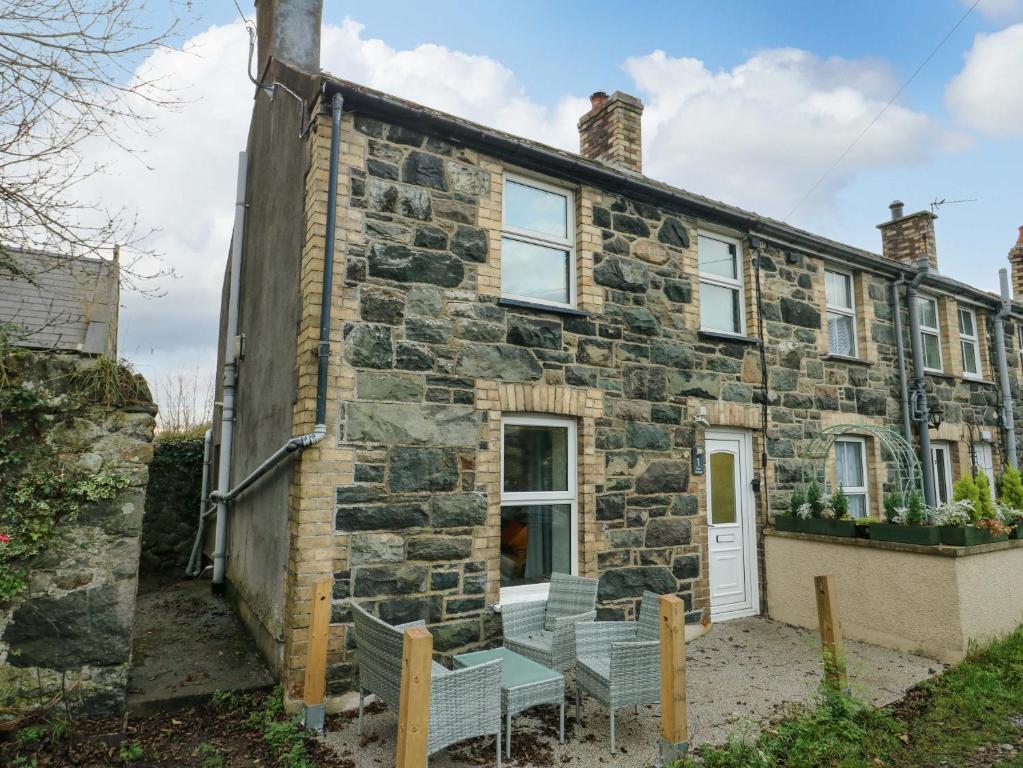 a stone house with chairs outside of it at 1 Dinas cottages in Caernarfon