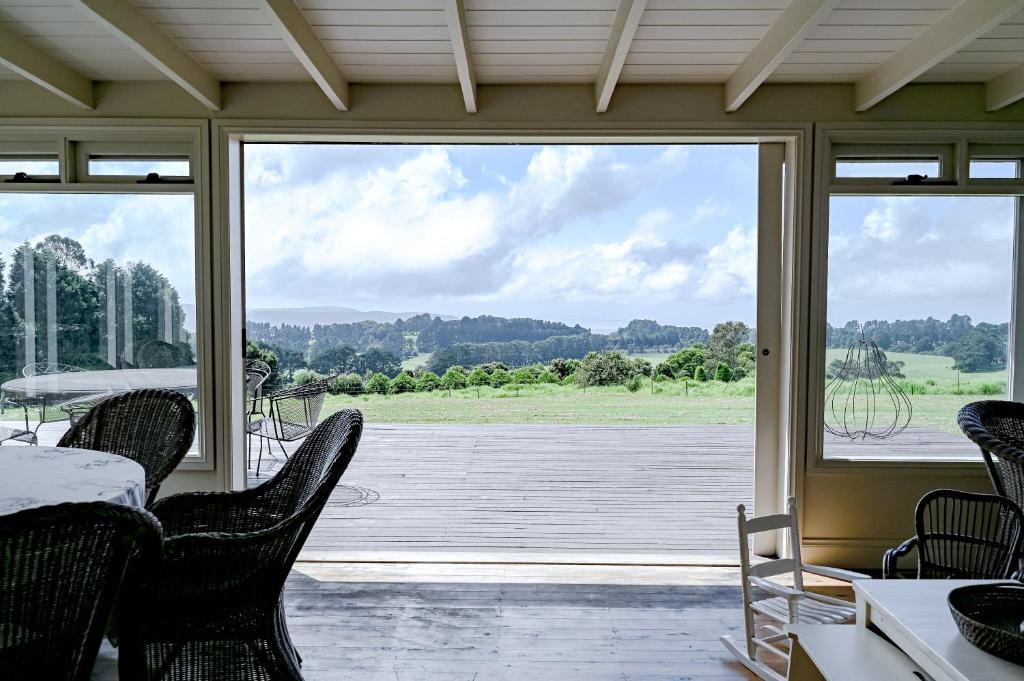 a screened in porch with chairs and a large window at Macksville Cottage Robertson in Robertson