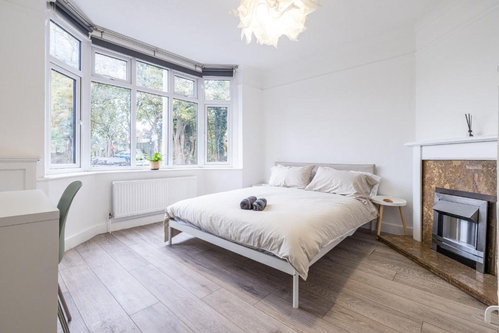 a white bedroom with a bed and a fireplace at Astrid Room - Kingsize minimalist room in Luton in Luton