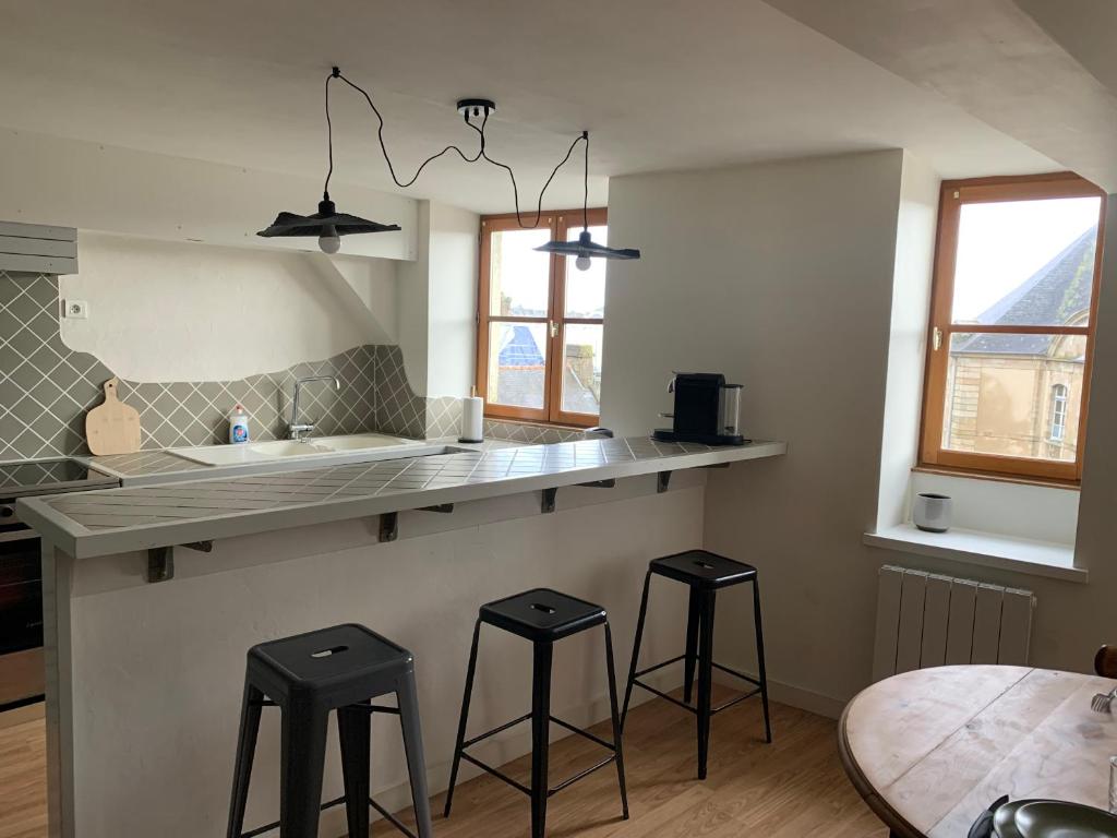 - une cuisine avec deux tabourets et un comptoir avec un évier dans l'établissement Aristide chic, à Fougères