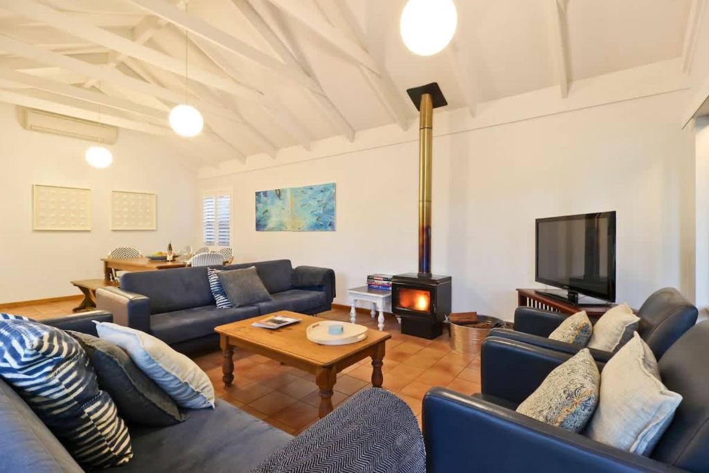 a living room with blue couches and a tv at The Quindy, family beach house in Quindalup