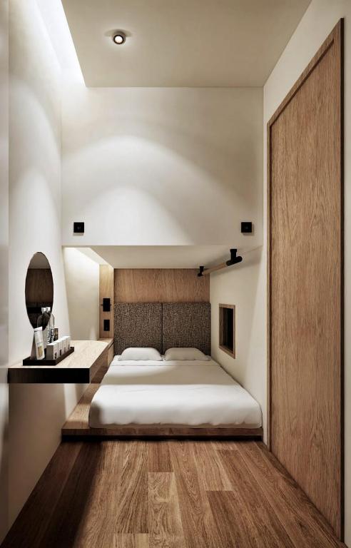 a bedroom with a large bed and a wooden floor at Althia Capsule Quarters in Badung