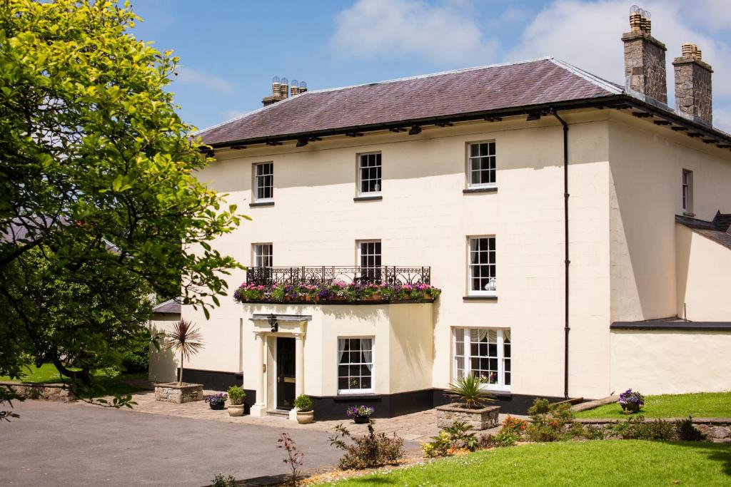 a white house with a balcony with flowers at Portclew House in Pembroke