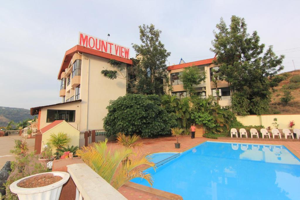 a hotel with a swimming pool in front of a building at Mount View Executive in Panchgani