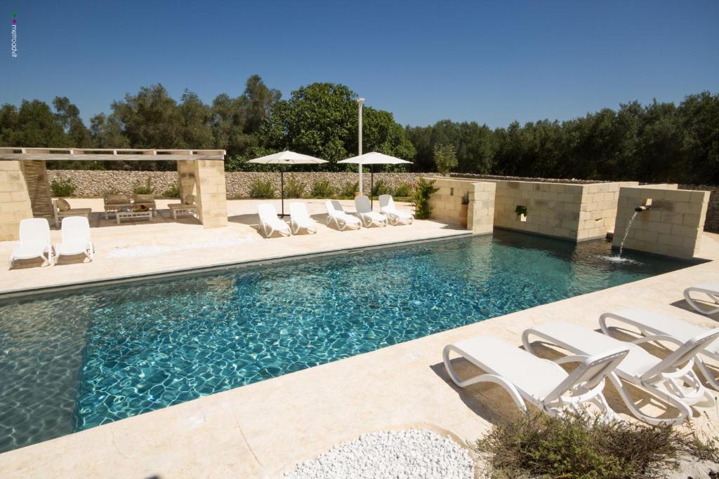 uma piscina com cadeiras e guarda-sóis em Agriturismo La Turrita em SantʼAndrea