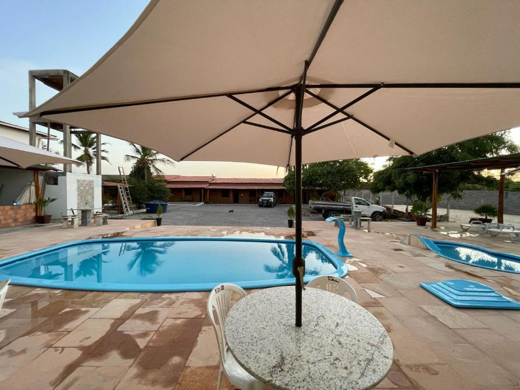 a table with an umbrella next to a swimming pool at Pousada Casa Grande in Barreirinhas