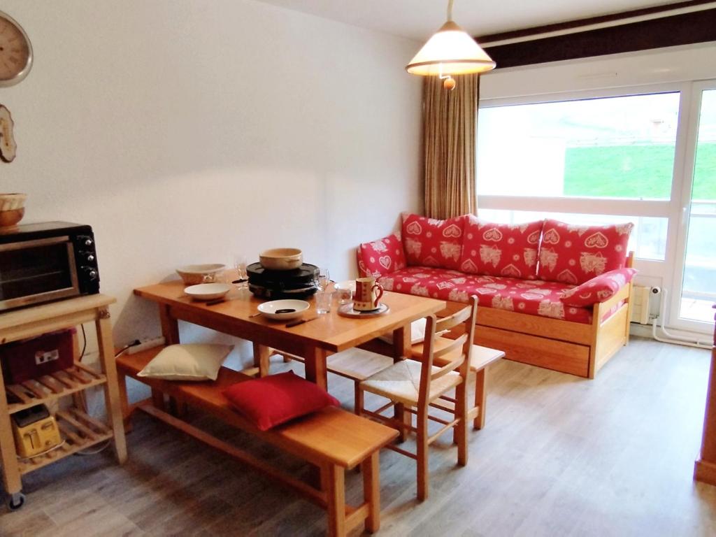 a living room with a table and a red couch at Charmant 2 pièces cabine, au pied des pistes de Prapoutel, balcon sud-est, ascenseur, 6 pers - FR-1-771-55 in Les Adrets