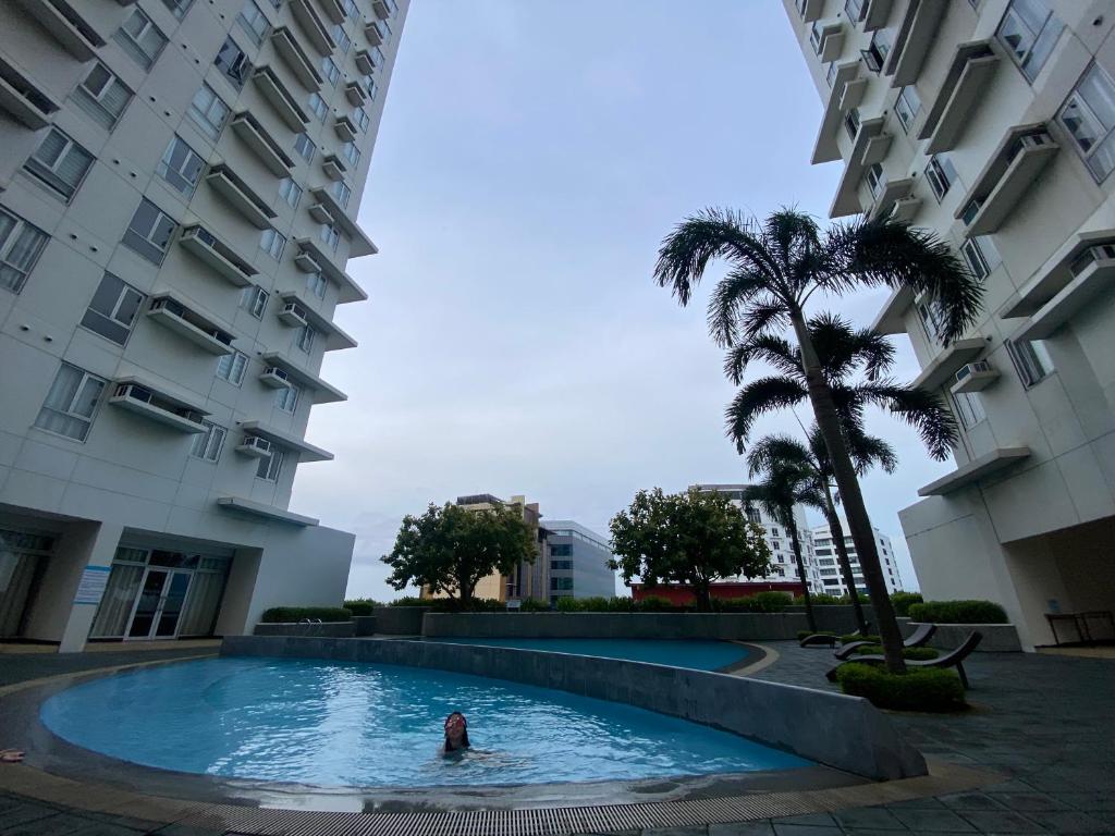 a person swimming in a swimming pool in front of a building at Condo near ATC- Molito Alabang, Muntinlupa in Manila