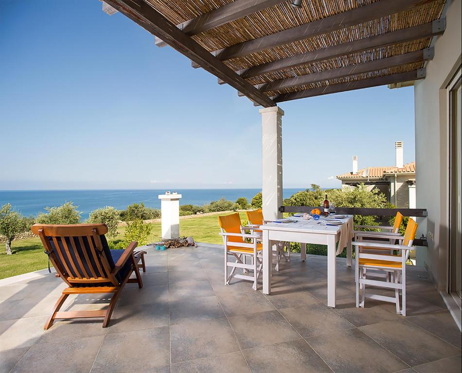 a patio with a table and chairs and the ocean at Ploes Villas in Skafidia