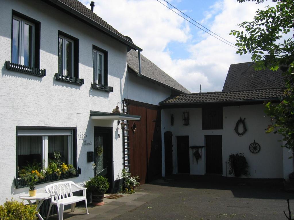 ein weißes Haus mit einer weißen Bank in der Einfahrt in der Unterkunft Villa Luzia in Meuspath