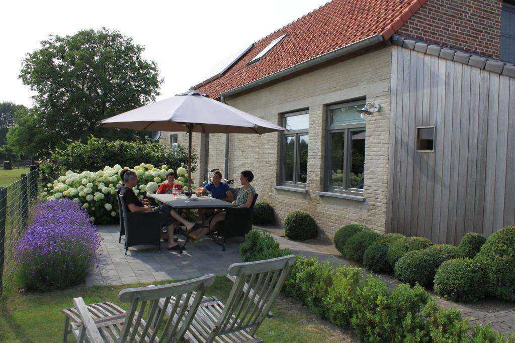 a group of people sitting at a table under an umbrella at B&B de Rijcke Rust in Rijkevorsel