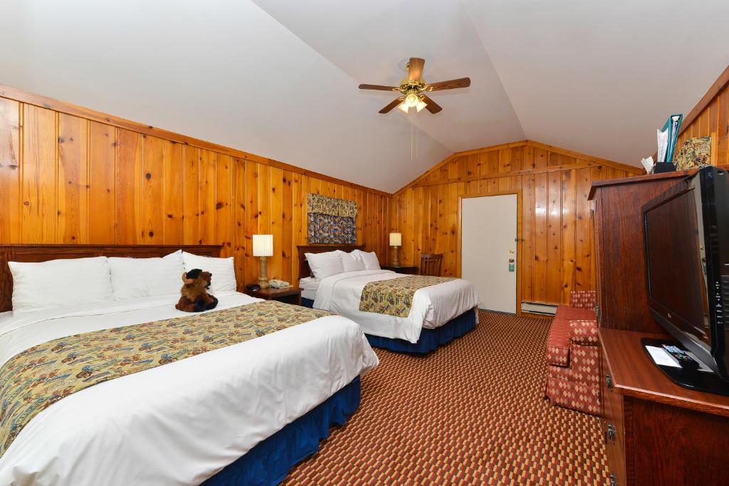a hotel room with two beds and a tv at Buffalo Bill Cabin Village in Cody