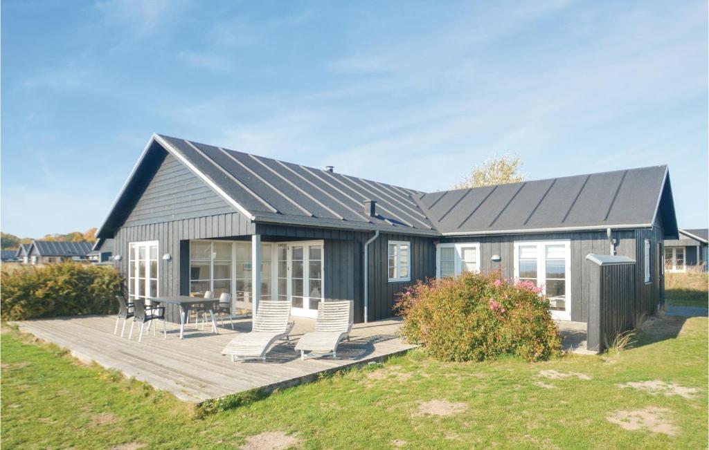 a house with a deck with chairs and a table at Four-Bedroom Holiday Home In Nysted in Nysted