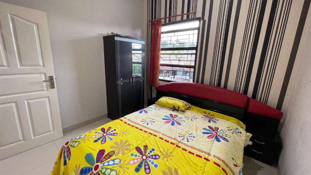 a bedroom with a bed with a yellow blanket and a window at Guest House Pesona Alam in Cijoho