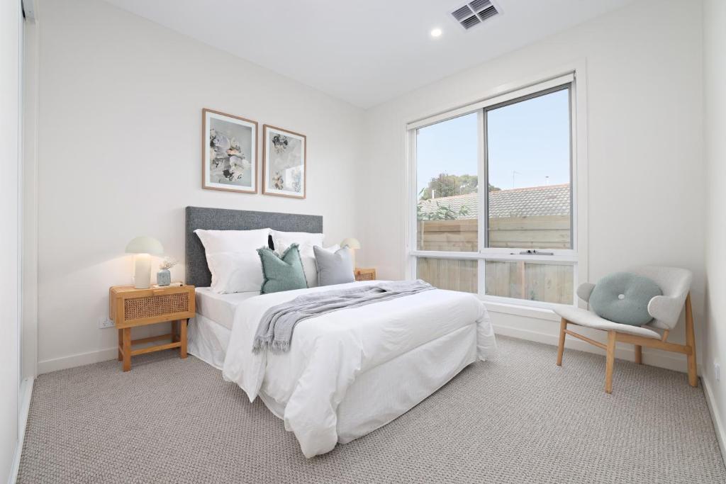 a white bedroom with a bed and a window at Bella Villa in Safety Beach