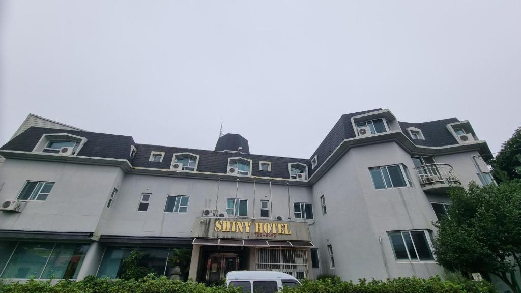 a large white building with a sign that reads shiny hotel at Shiny Hotel in Jeju