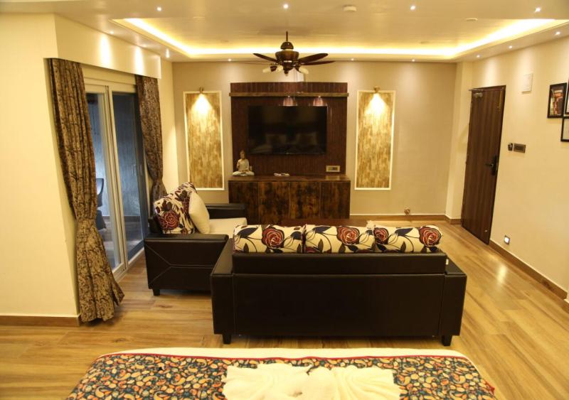 a living room with a couch and a tv at Dakshin Suites in Srīkākulam