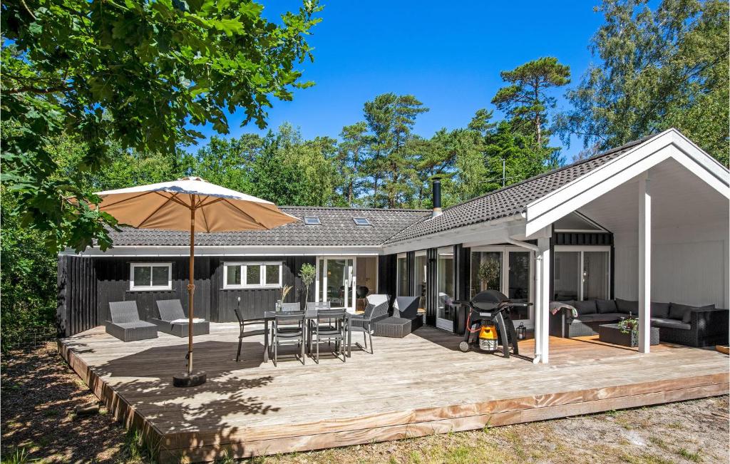 a wooden deck with an umbrella and a house at Holiday Home Tangvej Nexø Xii in Snogebæk