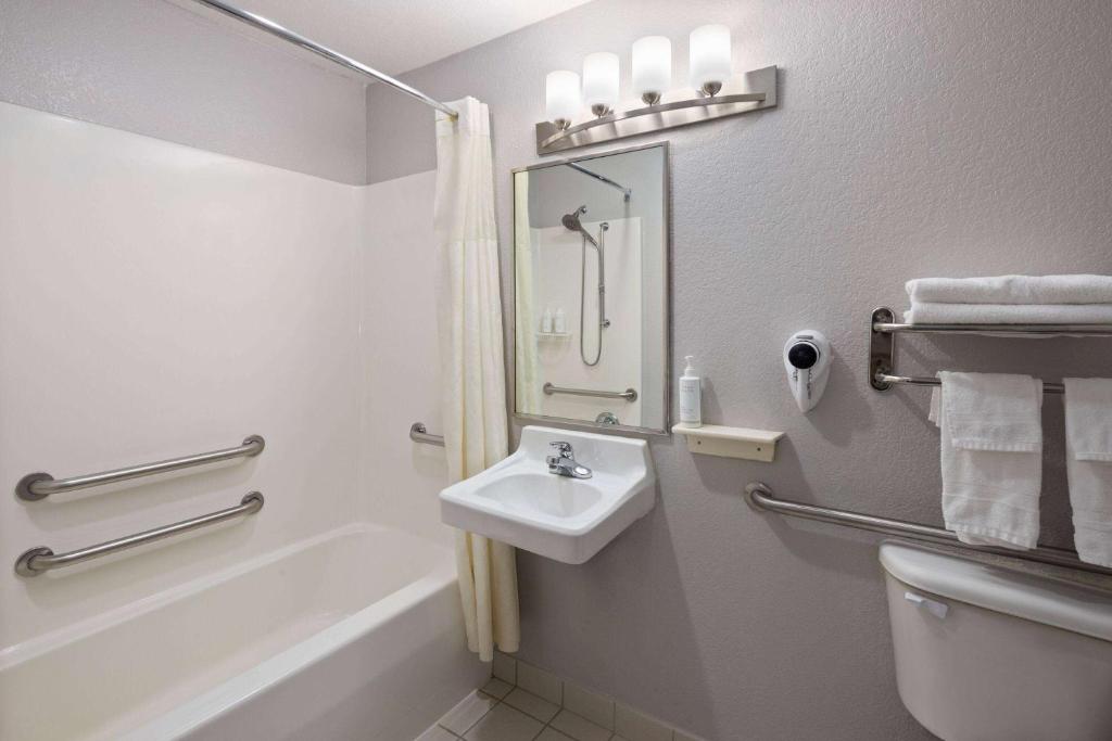 a bathroom with a sink and a tub and a toilet at Days Inn & Suites by Wyndham Green Bay WI in Green Bay