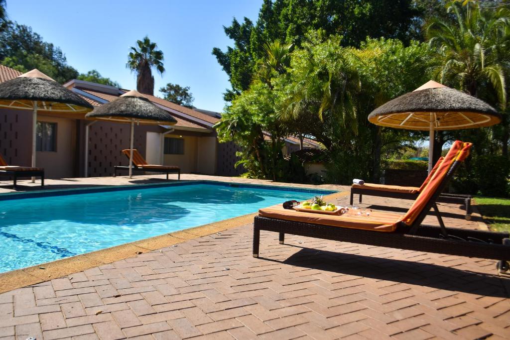 a swimming pool with a table and chairs and an umbrella at Cresta Bosele Hotel in Selebi-Pikwe