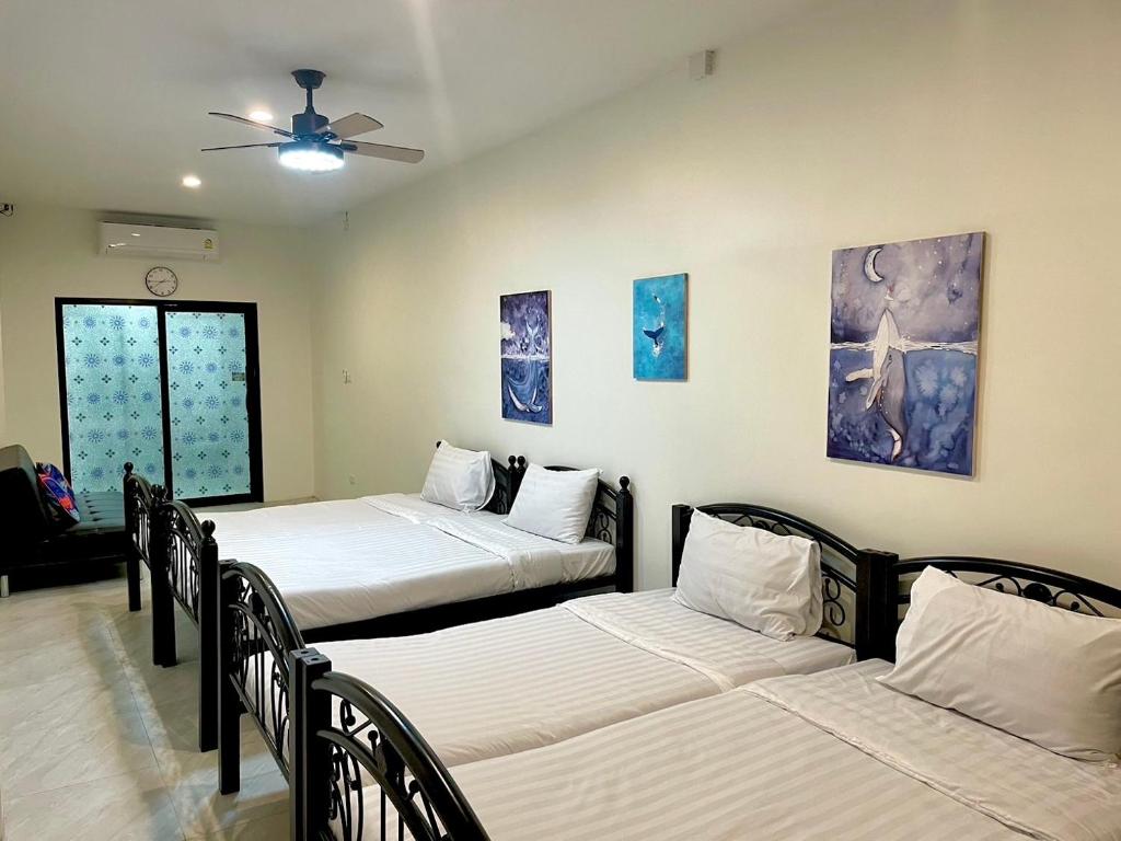 Zimmer mit 3 Betten und einem Deckenventilator in der Unterkunft PJ Hostel & Bar in Pattaya