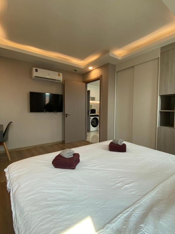 a bedroom with a large white bed with two towels on it at MAHIDOL CONDO มหิดลคอนโด in Chiang Mai