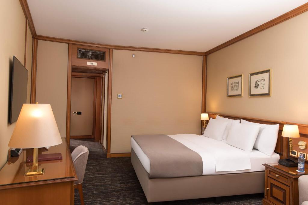 a hotel room with a bed and a table and lamp at Grand Hotel Bucharest in Bucharest