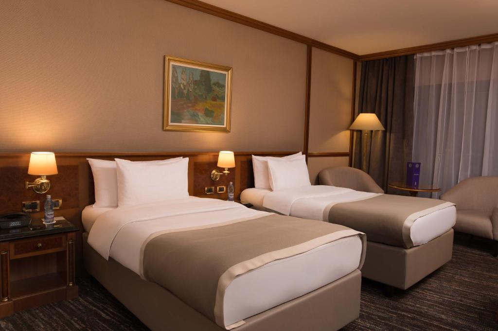 two beds in a hotel room with two lamps at Grand Hotel Bucharest in Bucharest