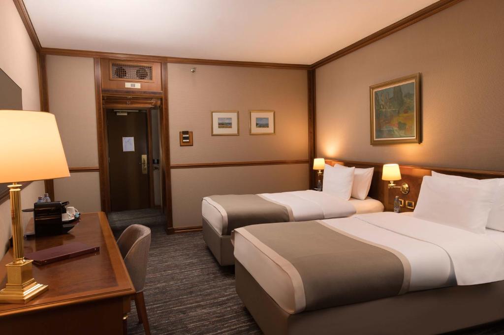 a hotel room with two beds and a desk at Grand Hotel Bucharest in Bucharest
