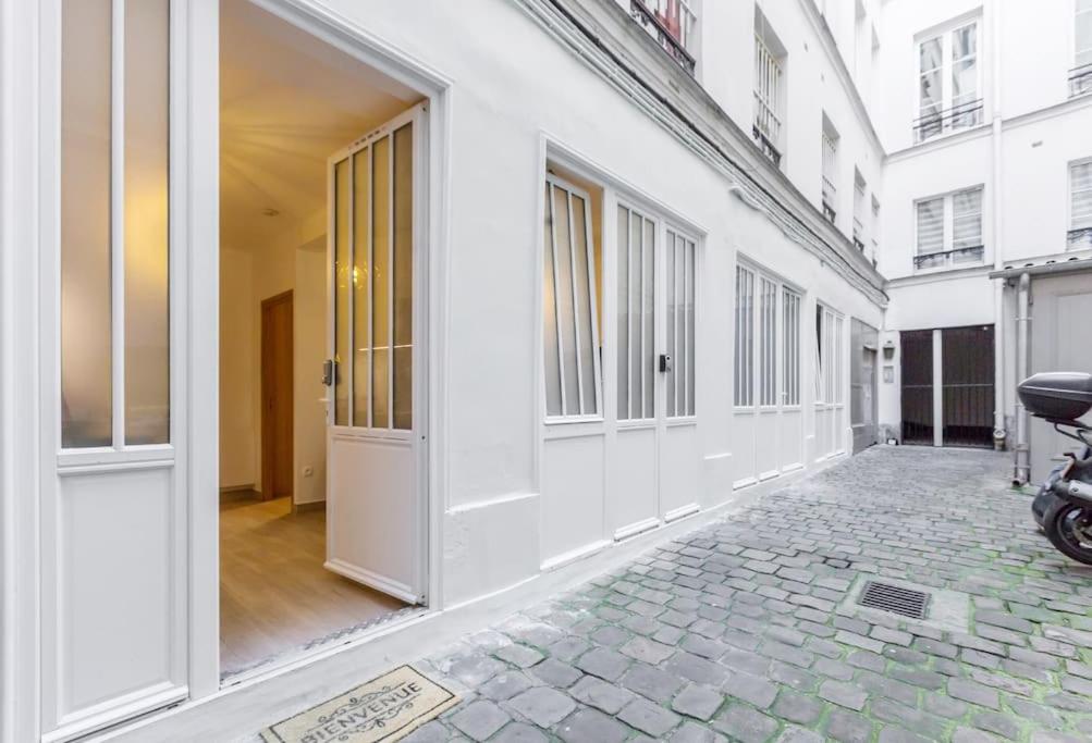 un couloir d'un bâtiment blanc avec une moto garée sur un trottoir dans l'établissement Lovely apartment in Louvre, à Paris