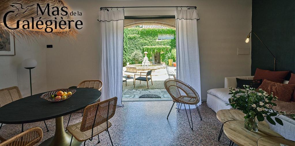 un salon avec une table et des chaises et un salon dans l'établissement Mas de la Galégière - Les Maisons, à Arles