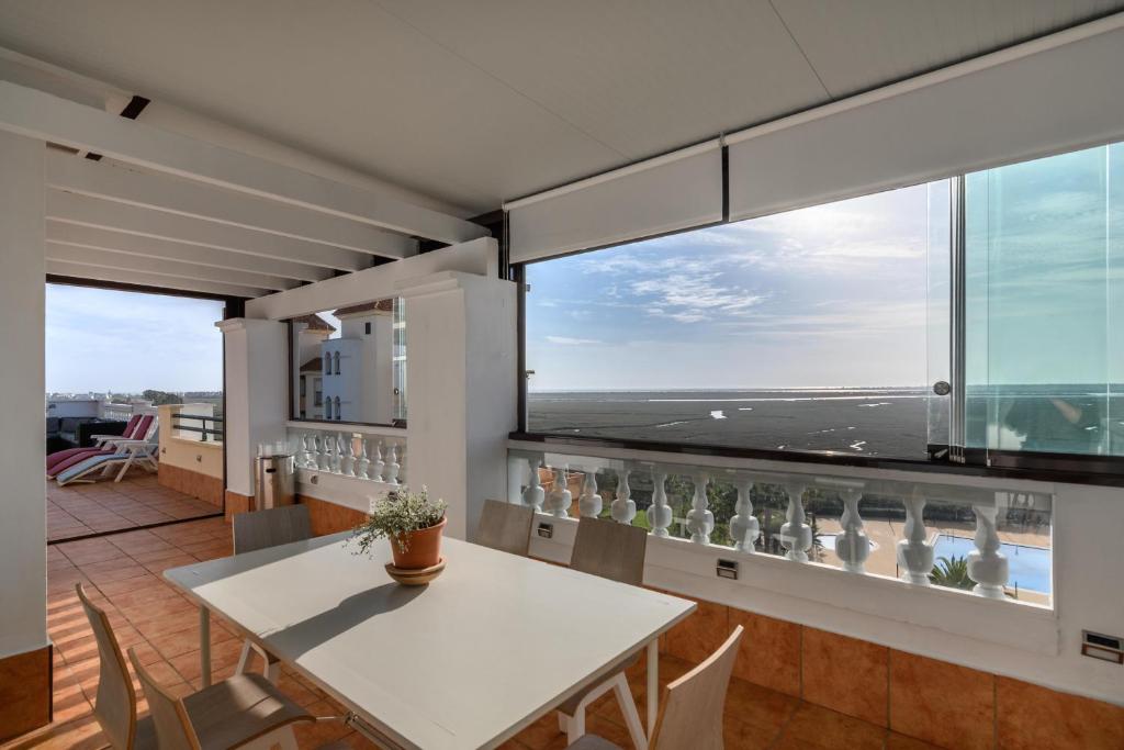 - une salle à manger avec une table blanche et une vue sur l'océan dans l'établissement Las Marismas Atico PLUS by Ĥ - Isla Canela Golf GLHM59P19, à Isla Canela