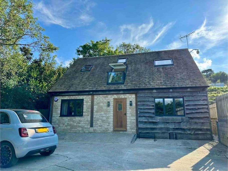 a small brick house with a car parked in front at Cuckoo Penn Hideaway - Luxury Cotswold Retreat in Gloucestershire