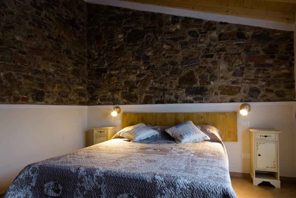 a bedroom with a bed and a stone wall at La corte dei tre in Torre del Lago Puccini