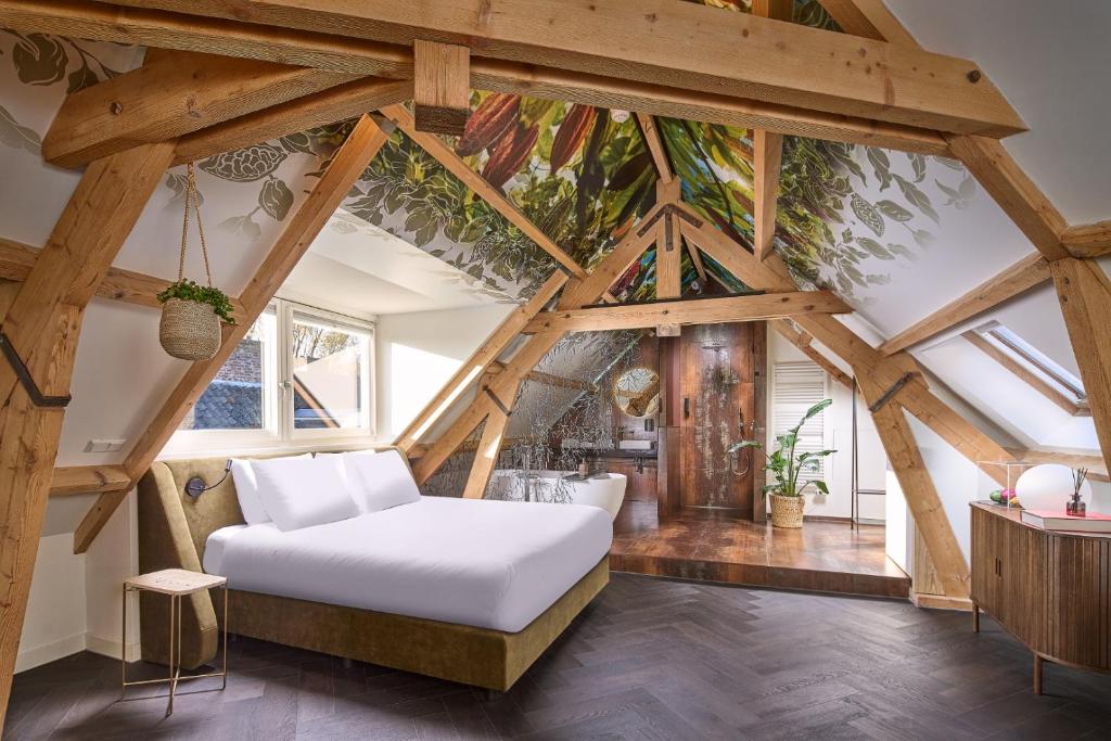 een slaapkamer met een wit bed op de zolder bij Boutique Hotel DARQ in Maastricht