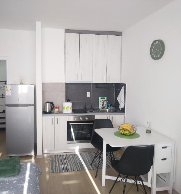 una cucina bianca con tavolo e frigorifero di Una Studio Apartman a Sombor