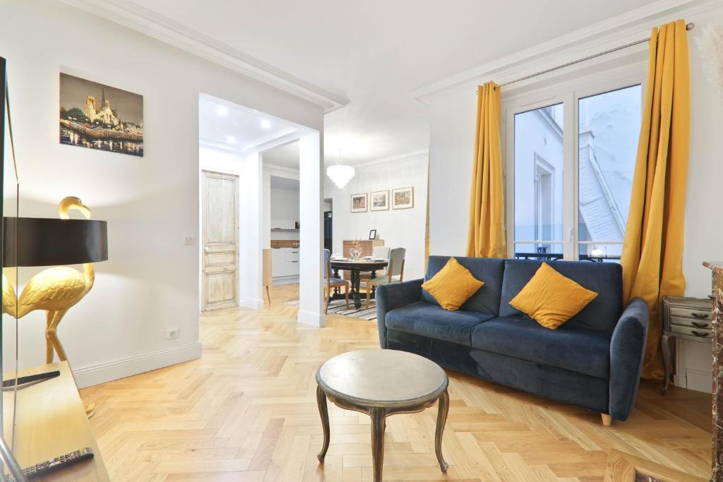 un salon avec un canapé bleu et une table dans l'établissement Charmant Appartement Arc de Triomphe Free Netflix, à Paris