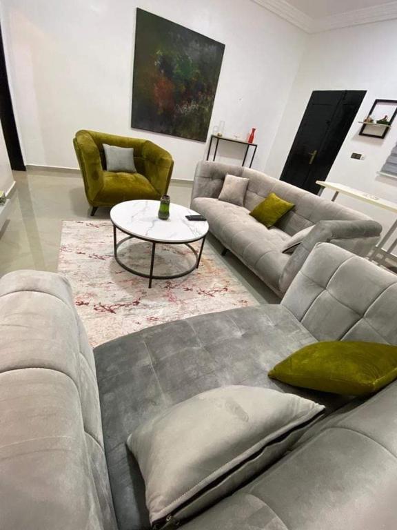 a living room with a couch and a table and chairs at Résidence ILEWA proche mer avec Terrasse Fidjrosse Cotonou in Cotonou
