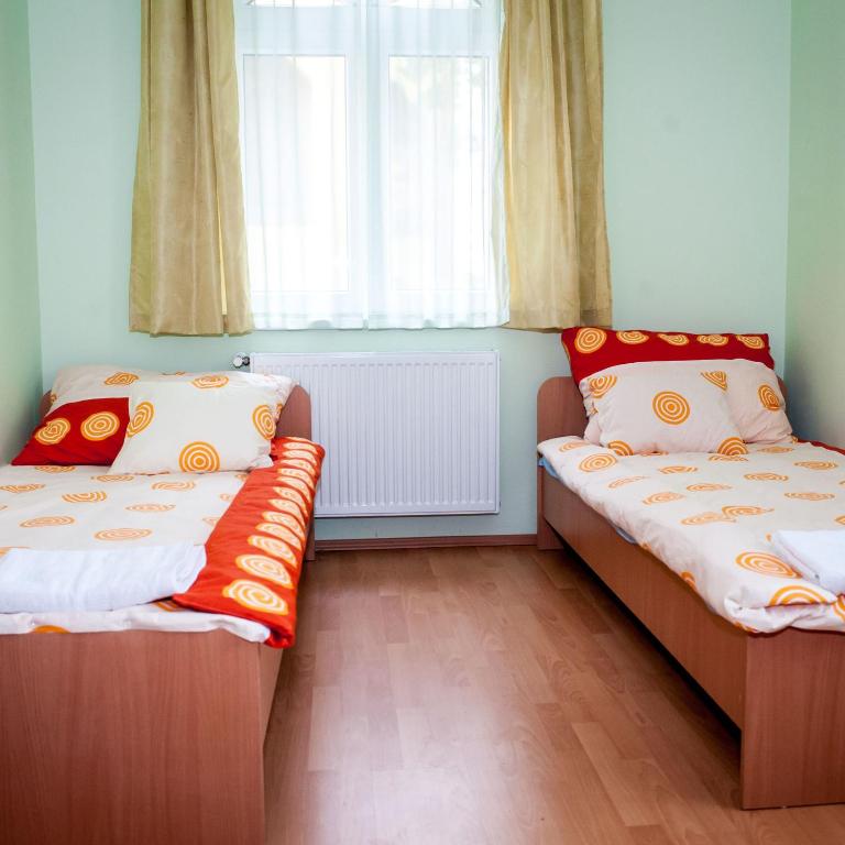 dwa łóżka pojedyncze w pokoju z oknem w obiekcie MAMRE Szálló w mieście Hajdúböszörmény