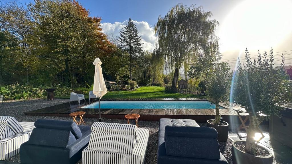een achtertuin met een zwembad en stoelen en een parasol bij Boutique Hotel Le Faucon in Valkenburg