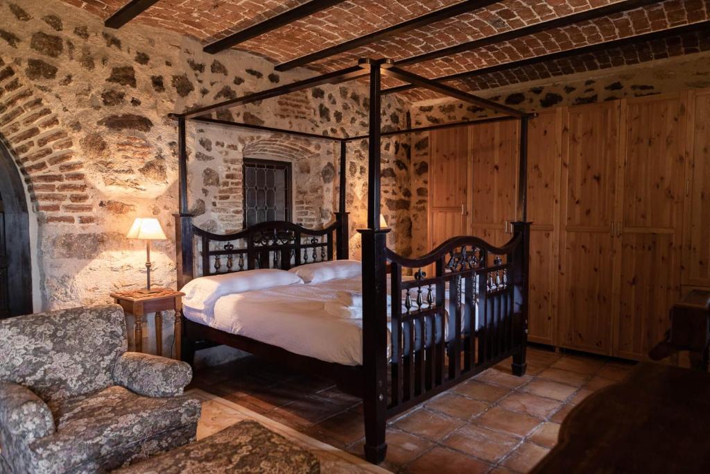 a bedroom with a canopy bed in a stone room at Casa Rural Doña Anita in Montánchez