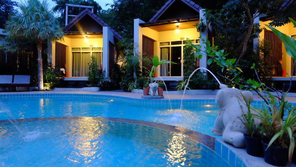 a swimming pool in front of a house at night at Baan Klang Aow Beach Resort in Ban Krut