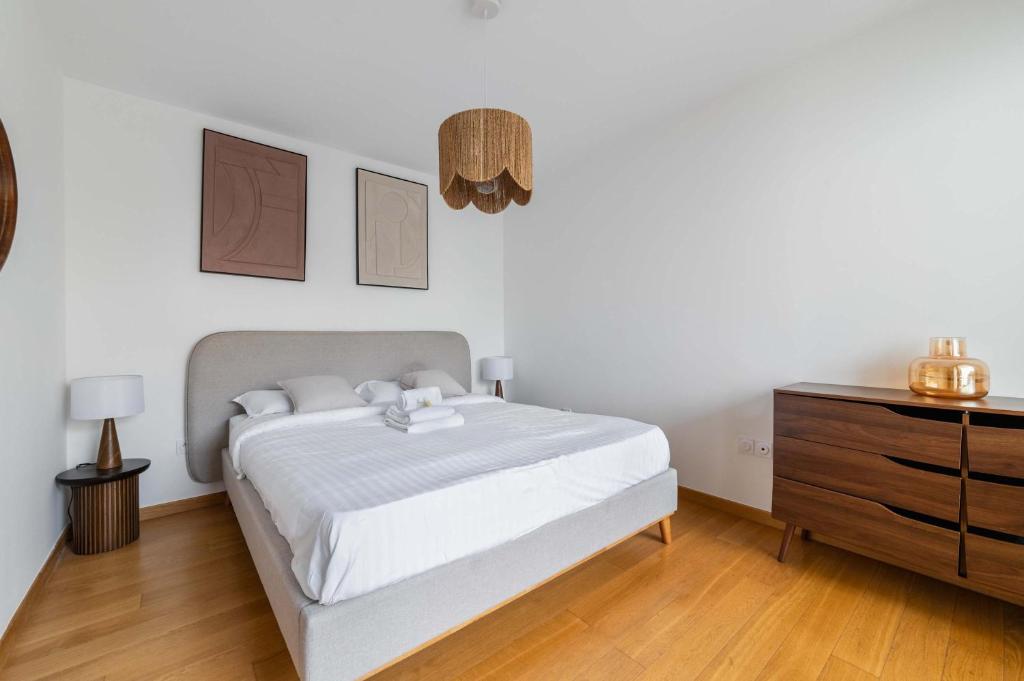 une chambre blanche avec un lit et une commode dans l'établissement Appartement lumineux avec terrasse Courbevoie - 4P - FLAT-GUEST, à Courbevoie