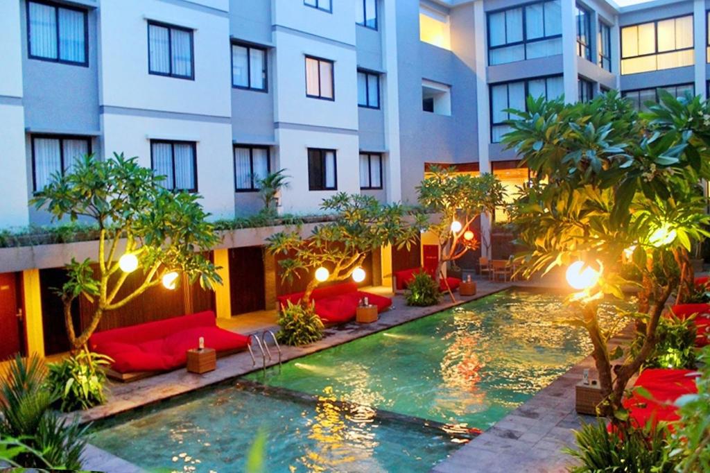 un hotel con piscina frente a un edificio en Hotel Dafam Savvoya Seminyak en Seminyak