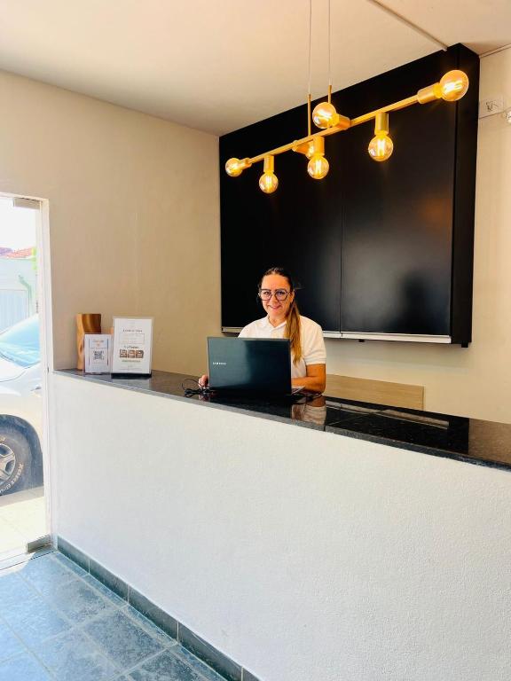 una mujer sentada en un mostrador con un portátil en Art Hotel, en Mogi Guaçu