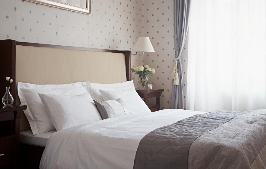 1 dormitorio con 1 cama con sábanas blancas y ventana en Apartments Almandine en Praga