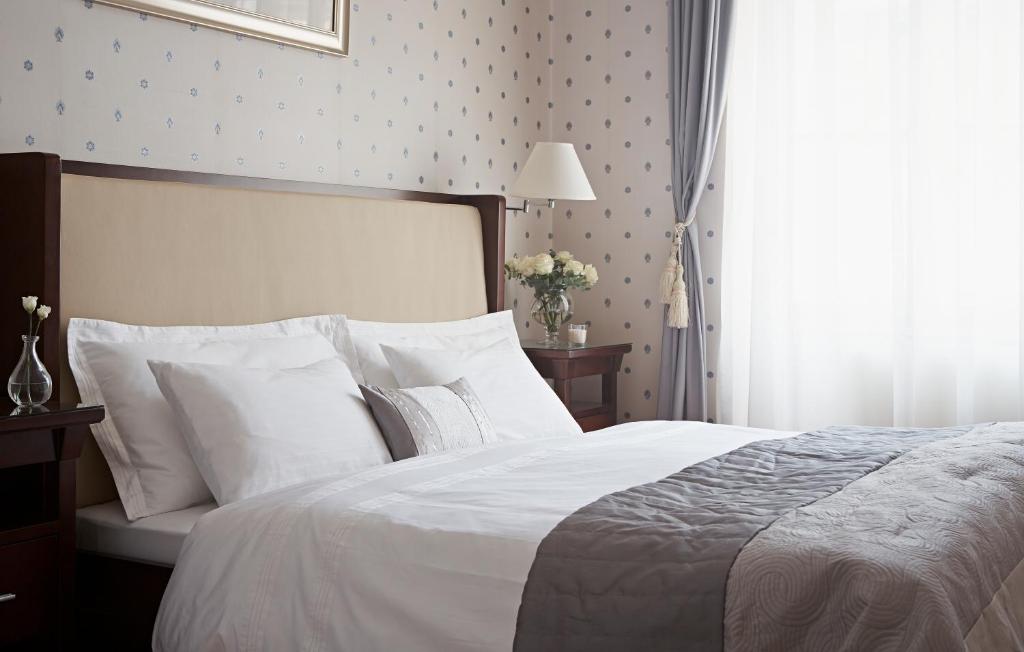 a bedroom with a bed with white sheets and a window at Apartments Almandine in Prague