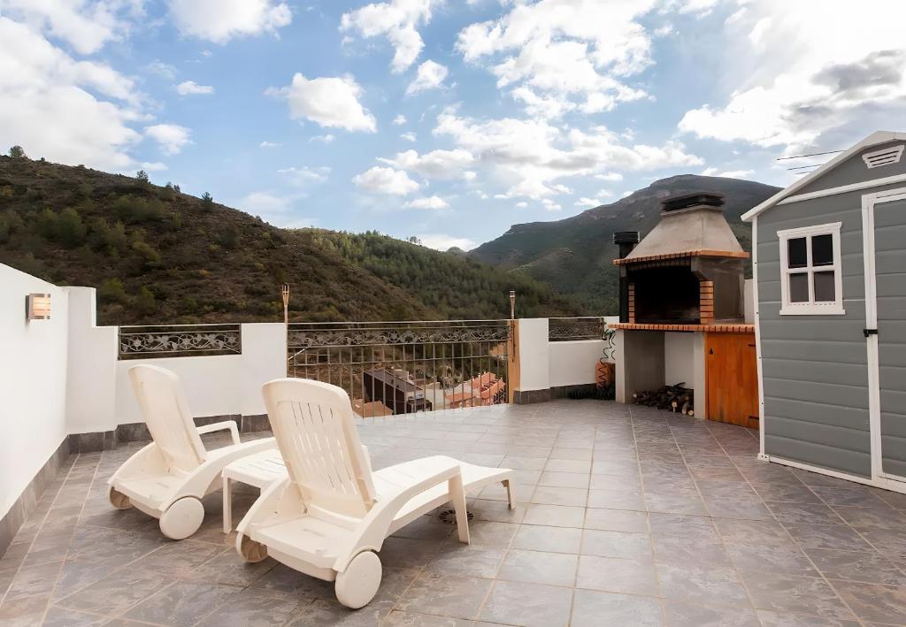 a balcony with two white chairs and a fireplace at Can Pitu in Alfondeguilla